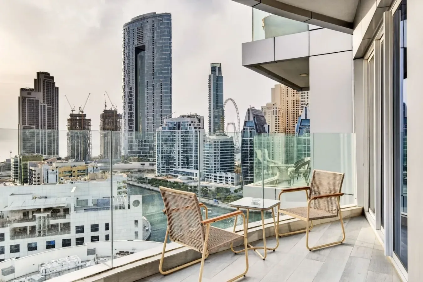 Una zona de estar en un balcón tiene vistas a varios edificios modernos de gran altura.