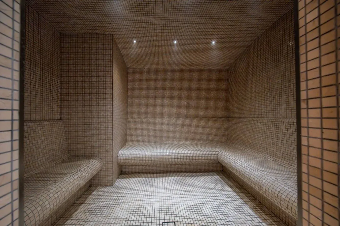 Un baño de vapor revestido de azulejos, con asientos integrados junto a las paredes.