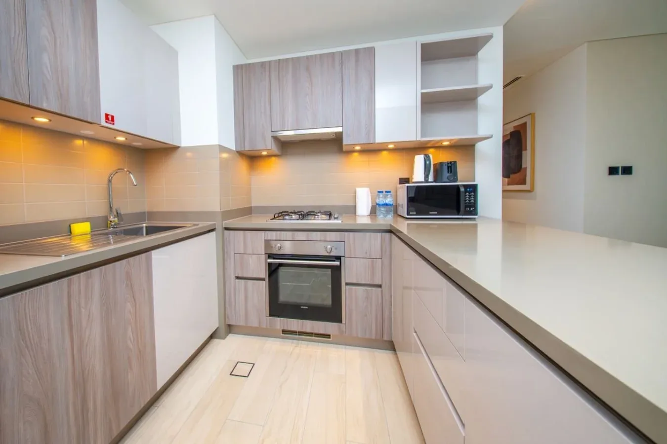Una cocina moderna con gabinetes de madera clara, un fregadero y un horno empotrado.