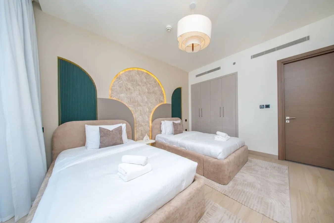 Dormitorio con dos camas, ropa de cama blanca y paneles decorativos en la pared.
