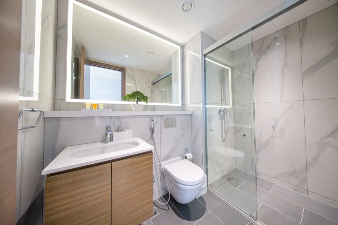 Un baño luminoso con lavabo, inodoro y ducha de vidrio.