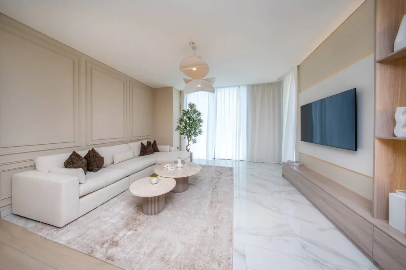 Una sala de estar luminosa con asientos, una mesa de centro y un televisor en la pared.