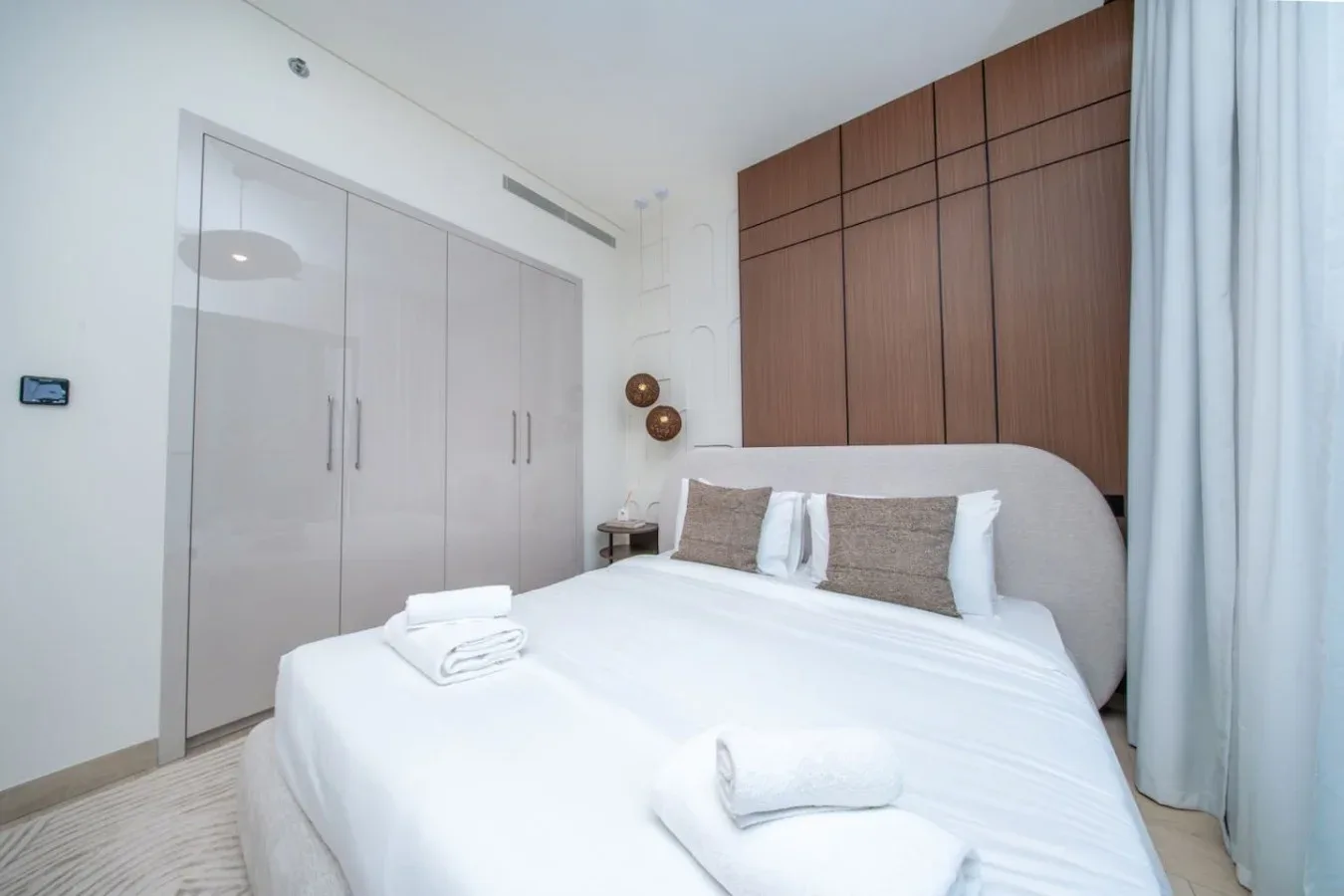 Un dormitorio luminoso con una cama tendida y armarios empotrados.