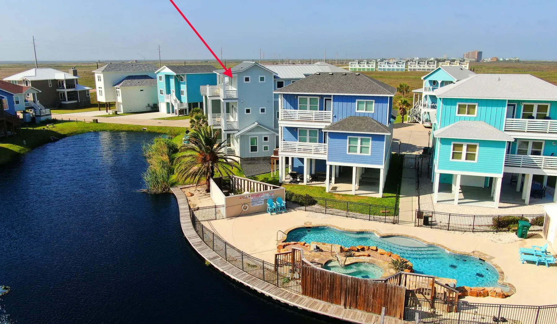 Aerial view of colorful waterfront homes surrounding a swimming pool and canal.