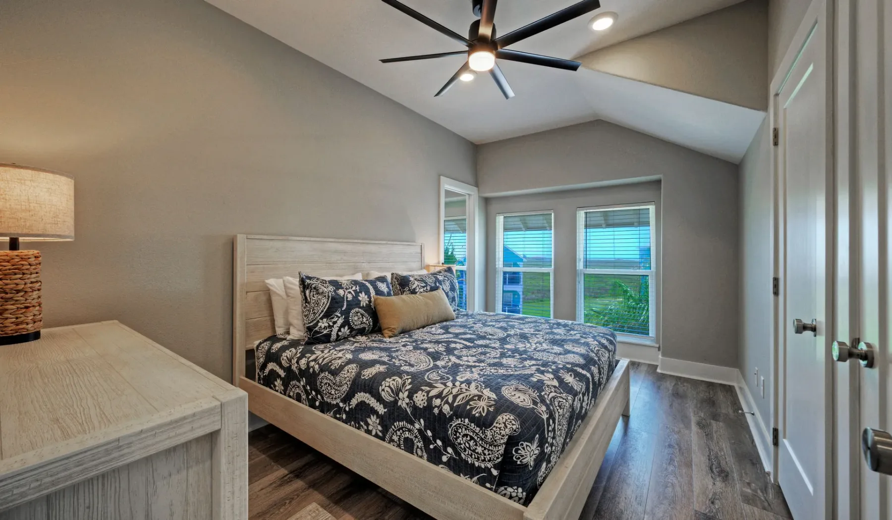 A bedroom with a bed beneath a vaulted ceiling and windows.