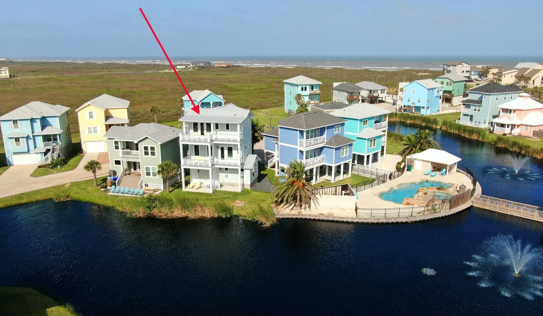 Vista aérea de casas junto a un canal, con una piscina al lado de las viviendas.