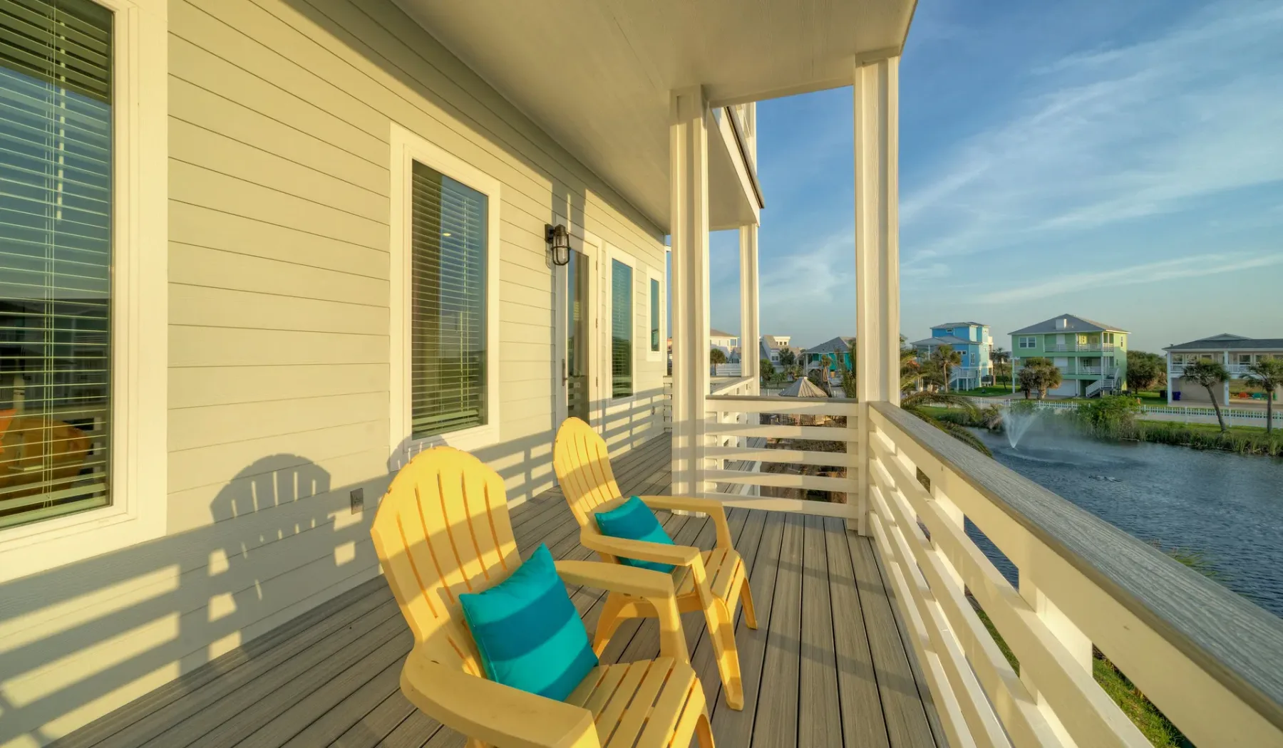 A wooden deck with outdoor seating overlooks a waterfront neighborhood.
