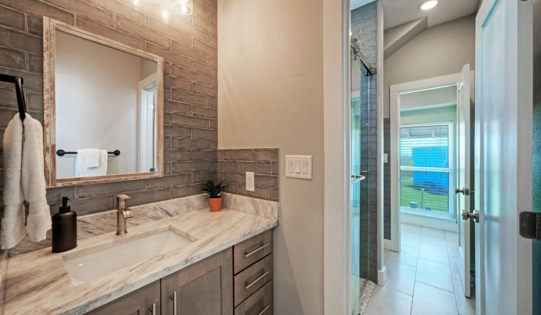 A bathroom vanity with a large mirror beside a glass shower.