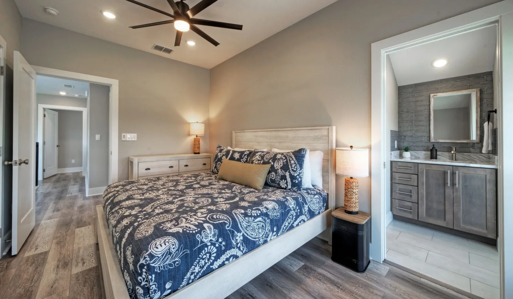 A bedroom with a patterned bed and an open doorway to a bathroom.