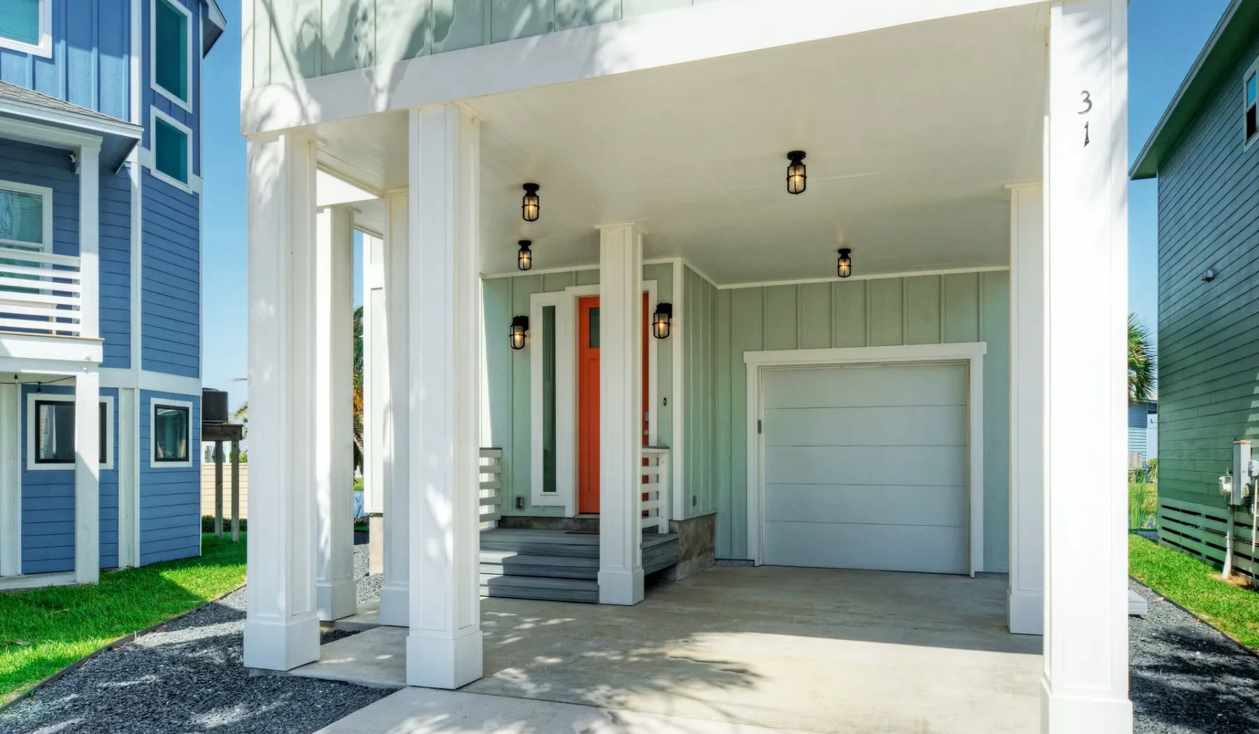 A covered exterior entry and garage beneath a raised home.