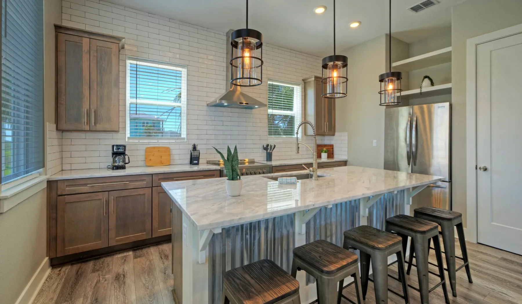 Una cocina luminosa con una gran isla, lámparas colgantes y gabinetes de madera.