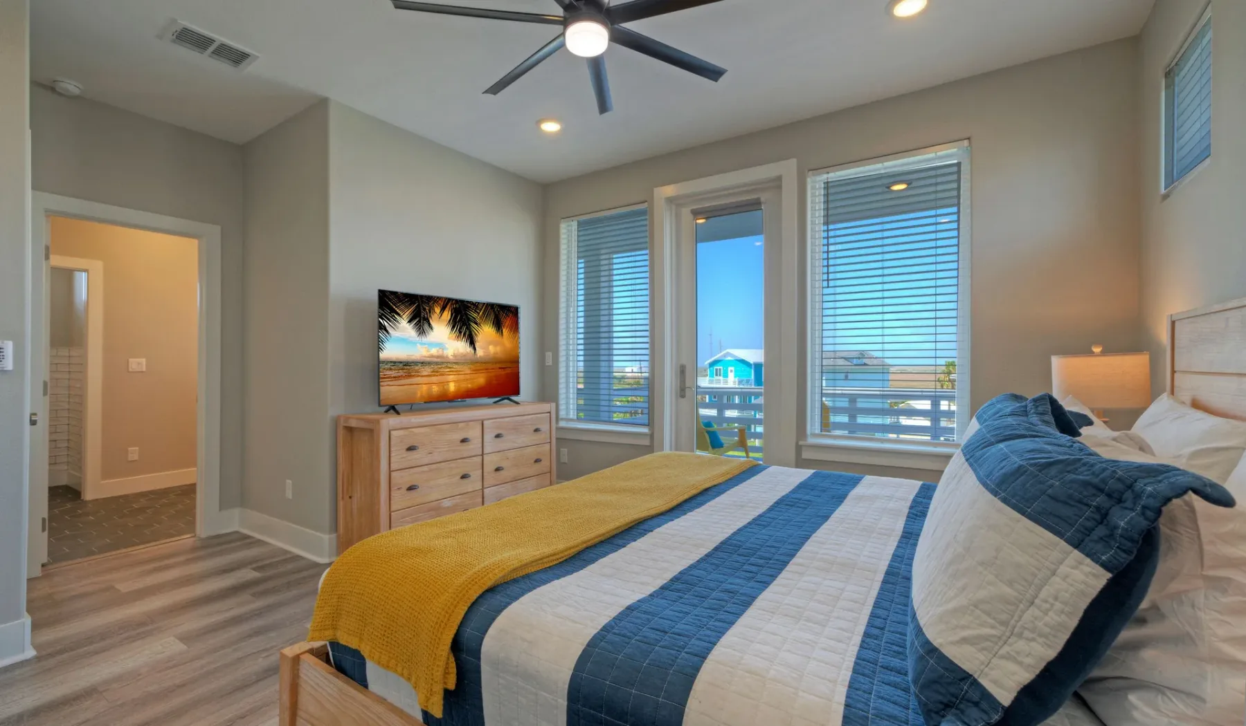 A bedroom with a bed, dresser, and windows overlooking the water.