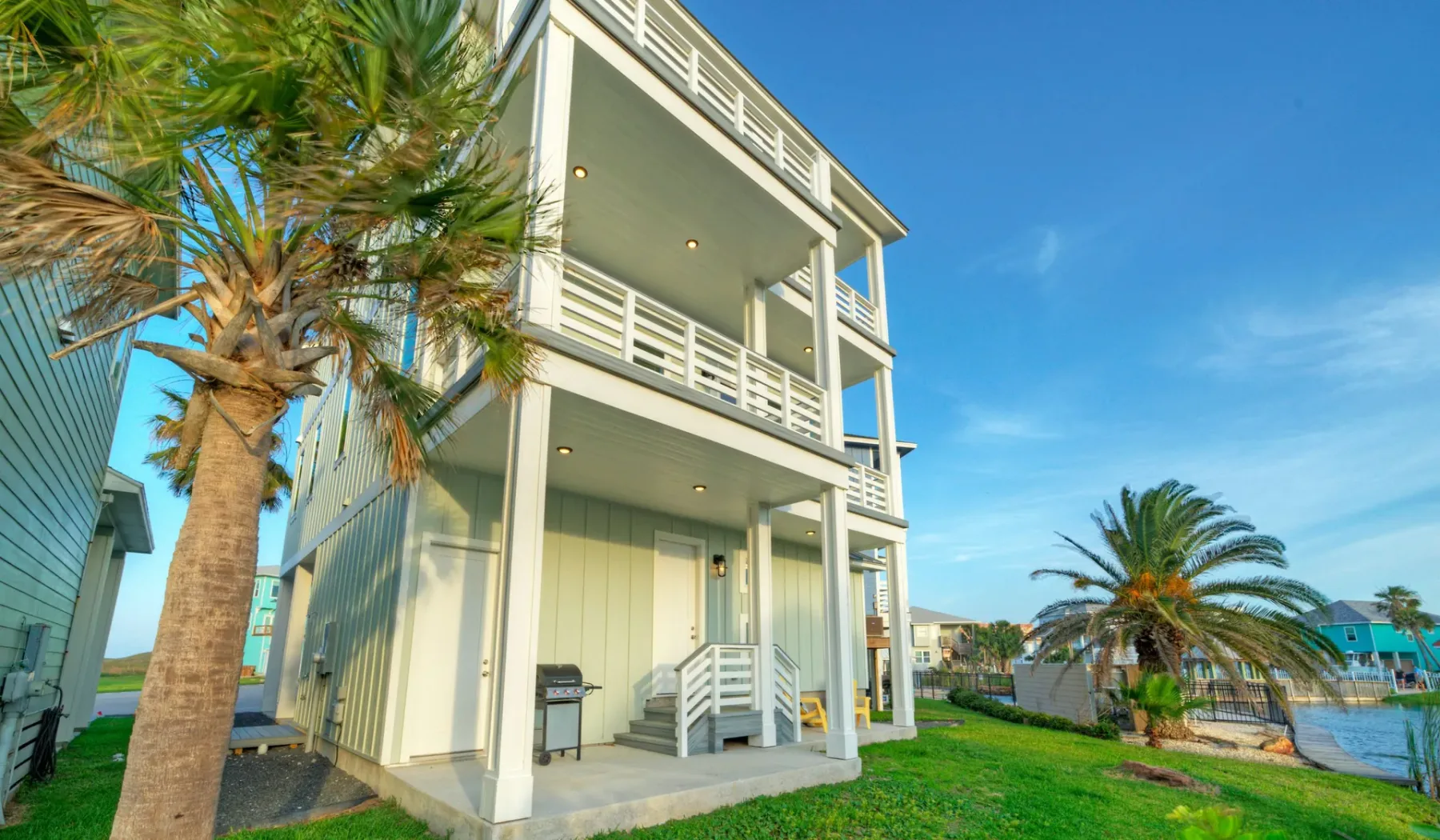 A multi-story coastal house with open balconies stands beside the water.