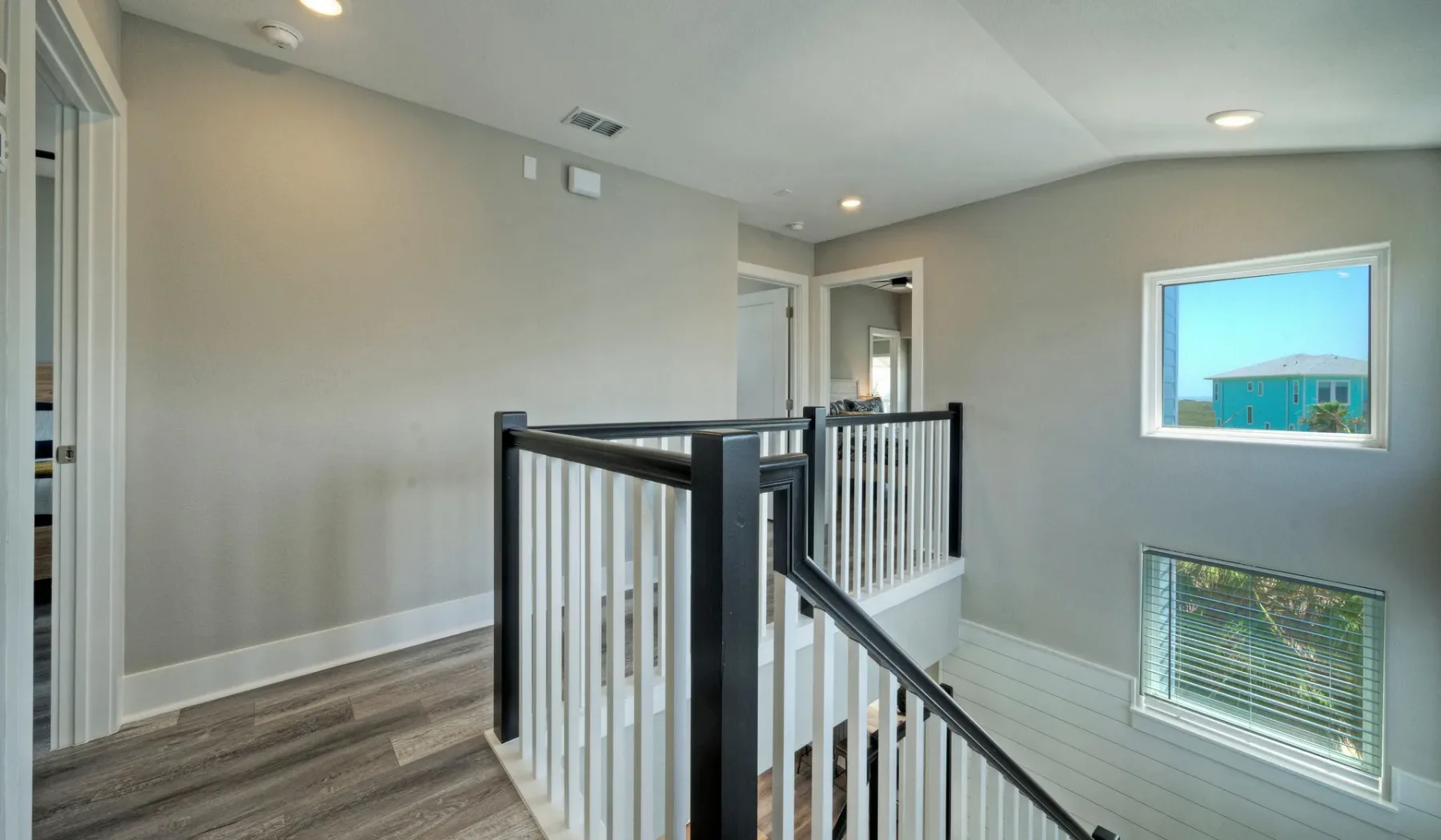 Interior stair landing with white railings and two windows.