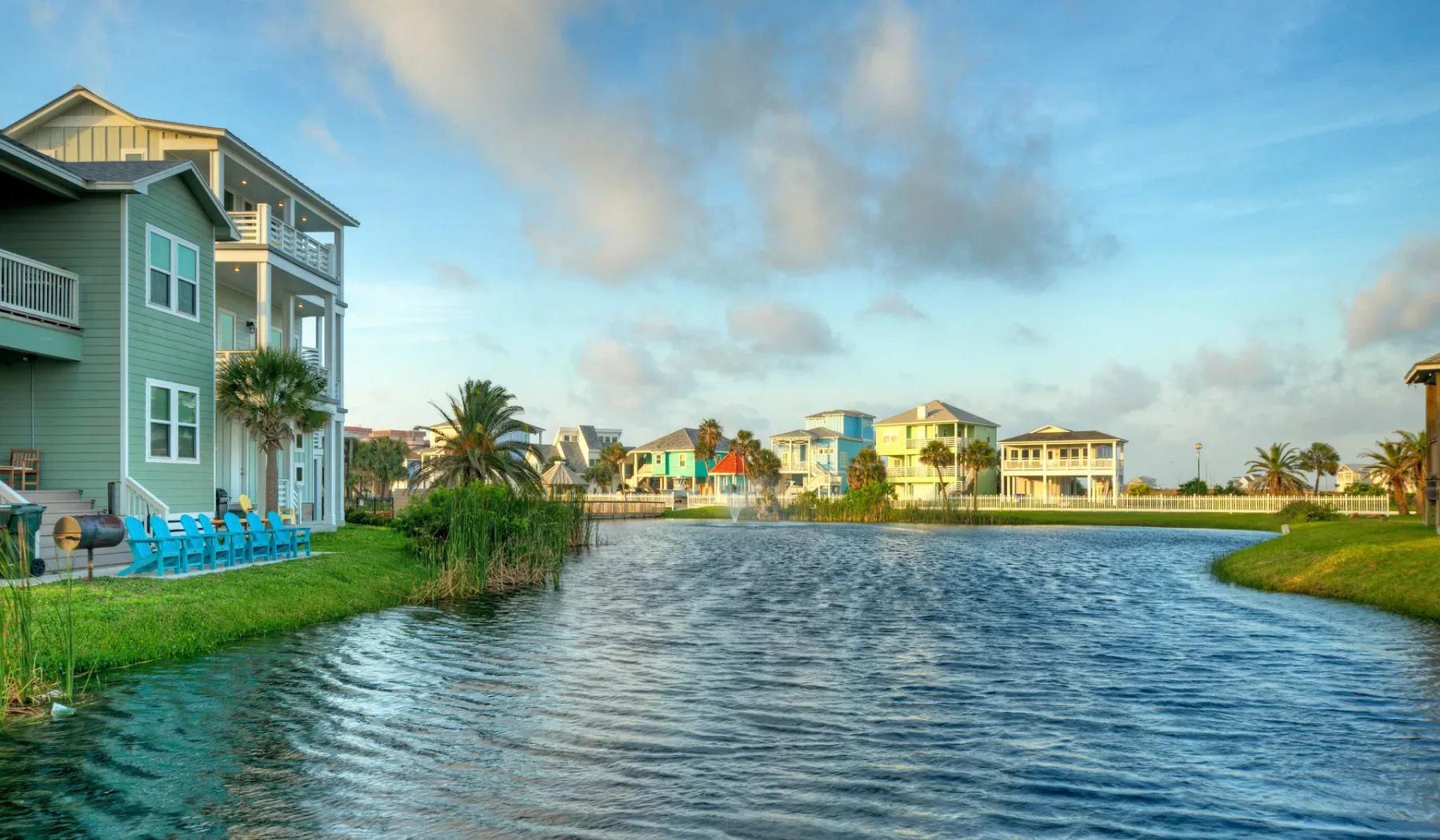 A waterfront scene shows colorful houses along a calm, rippling waterway.