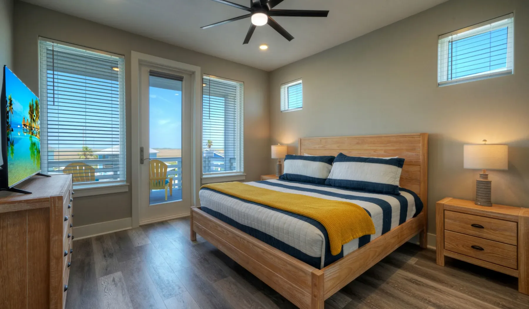 A bedroom with a wooden bed, striped bedding, and windows overlooking the water.