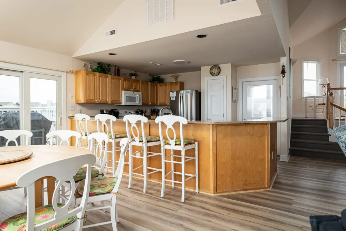 Cocina y comedor abiertos con una isla de madera y asientos altos.