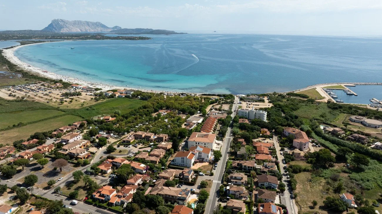 Aerial view of a coastal neighborhood beside a broad turquoise bay.