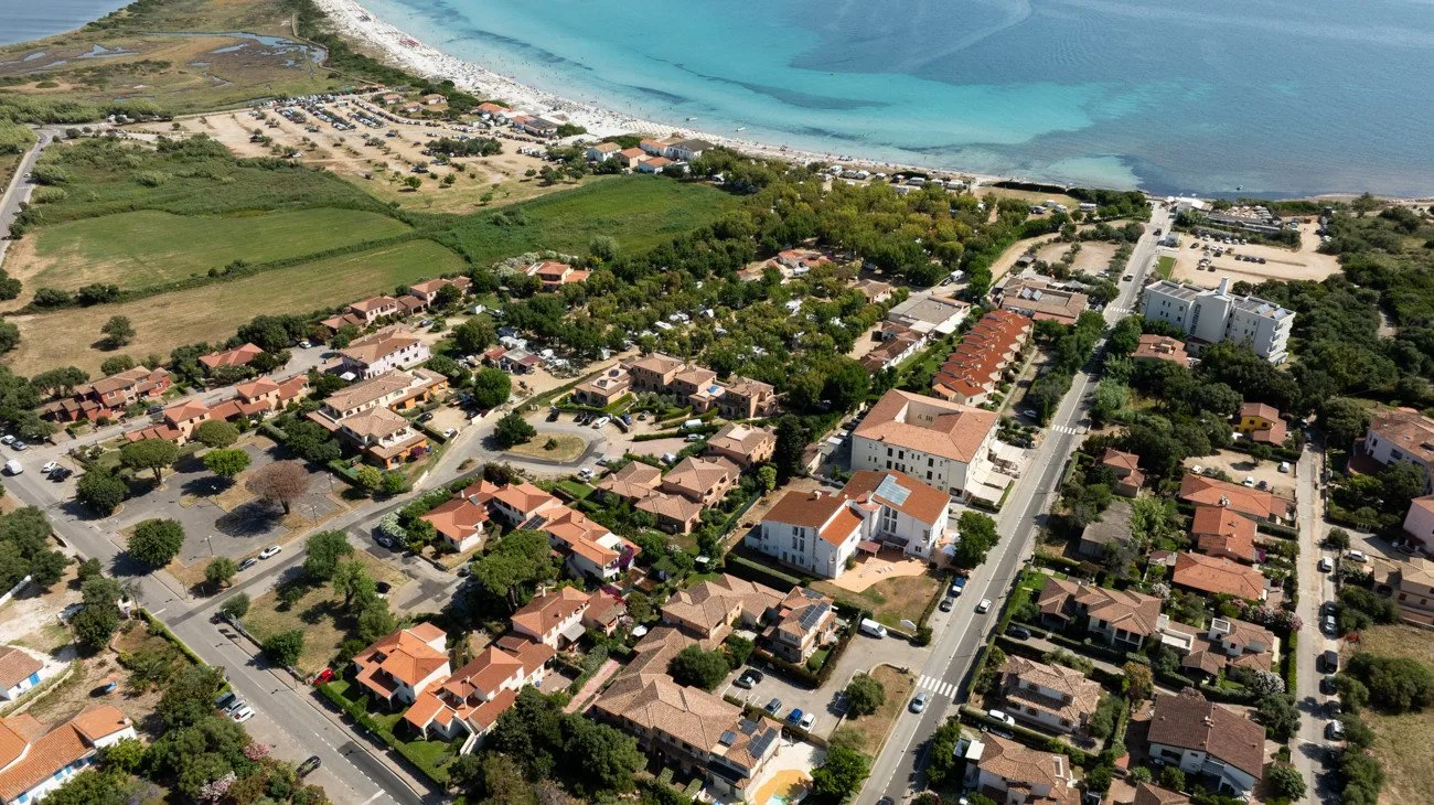 Aerial view of a coastal neighborhood with homes, roads, and turquoise water.