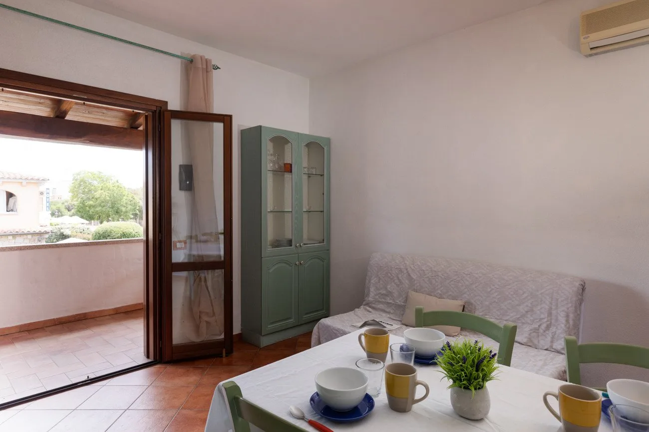 A living and dining area with a table set with dishes beside a sofa.