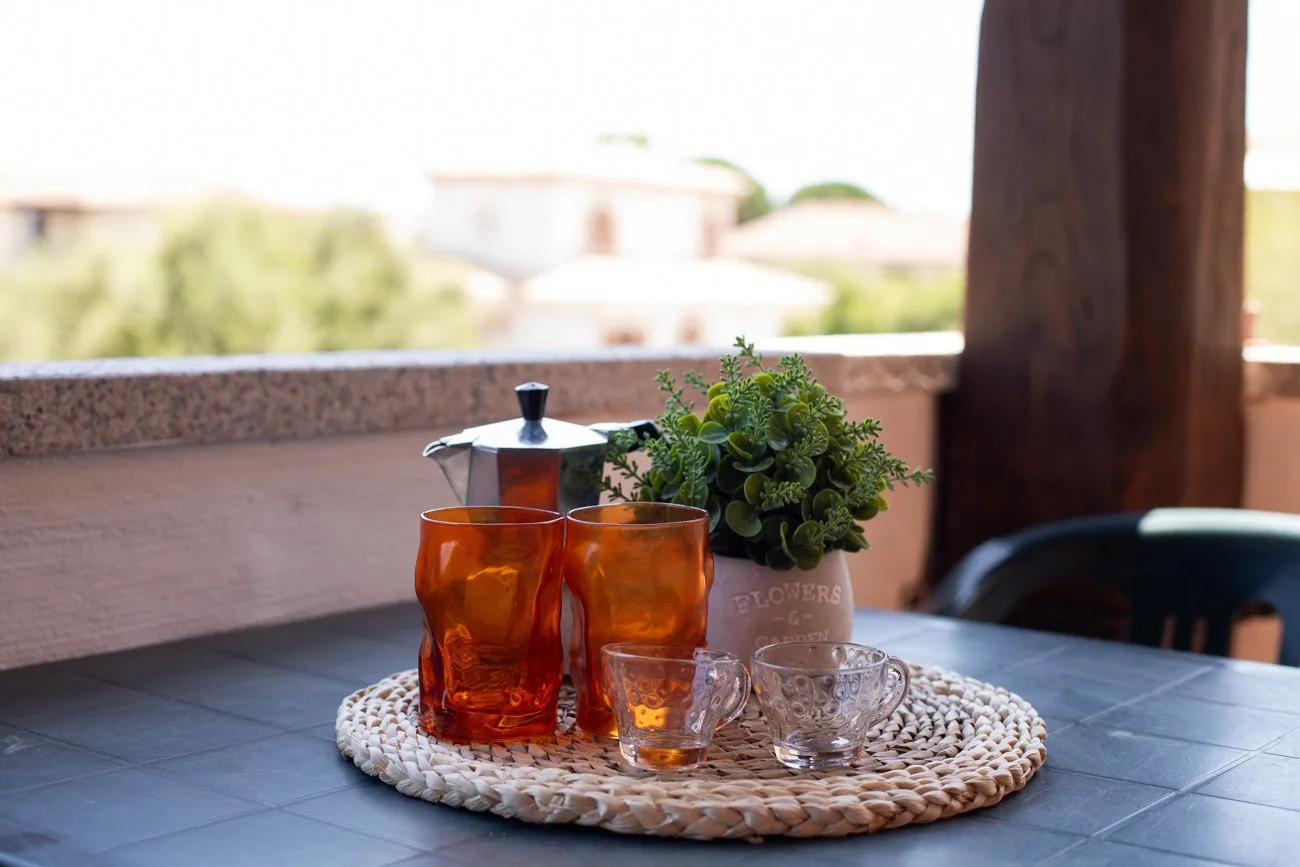 A table on an outdoor terrace holds glassware and a small potted plant.