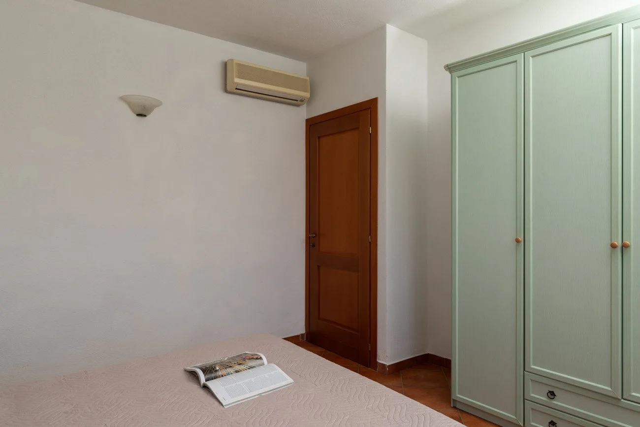 A bedroom with a bed, wooden door, and pale green wardrobe.
