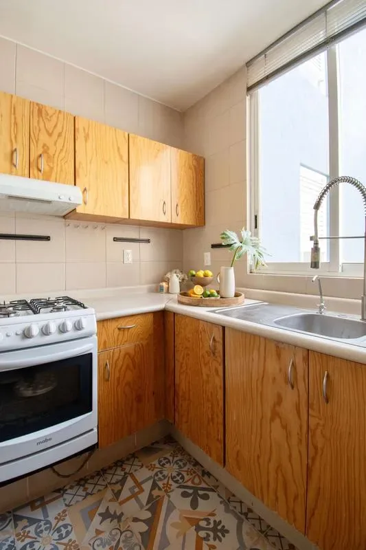 A compact kitchen with wooden cabinets, a gas stove, and a sink by the window.