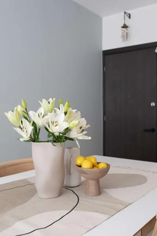 A dining table holds white flowers and a bowl of lemons beside a dark door.