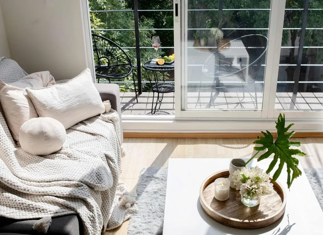 A bright sitting area beside sliding glass doors opens onto a small balcony.