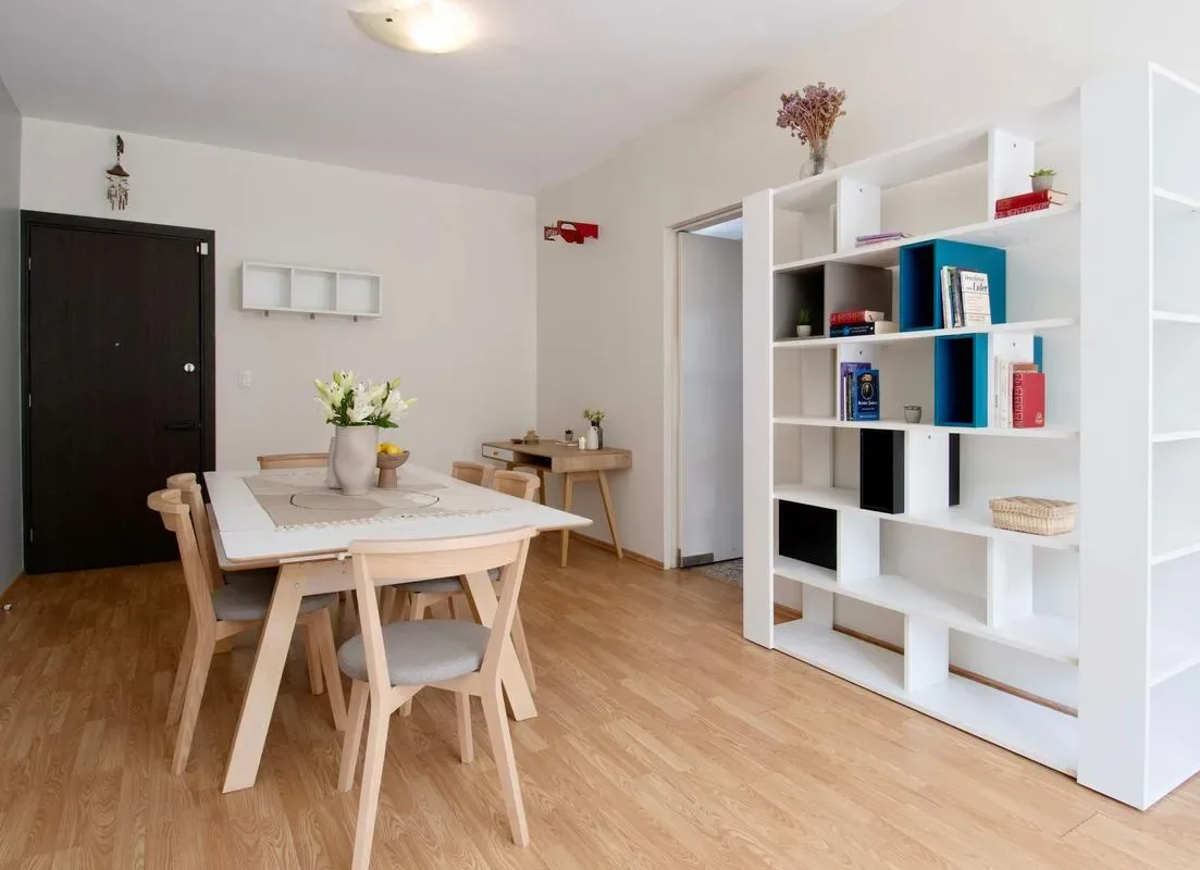 A bright dining area with a table and open shelving along the wall.