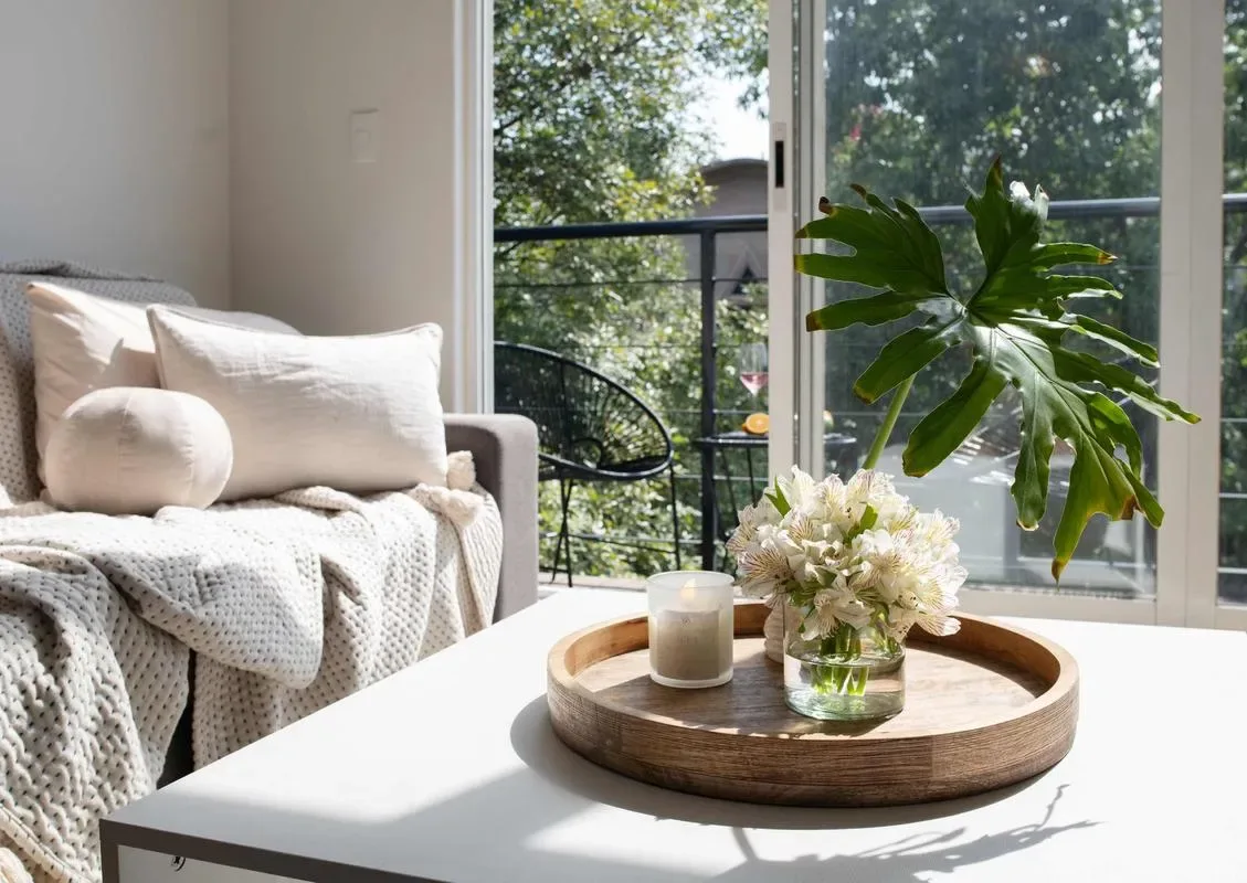 A bright living room with a sofa and a coffee table beside large windows.