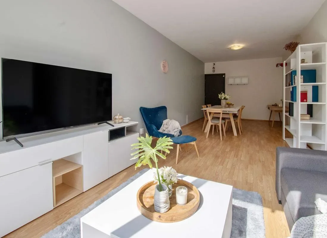 A living room with a television, seating, and a dining table.