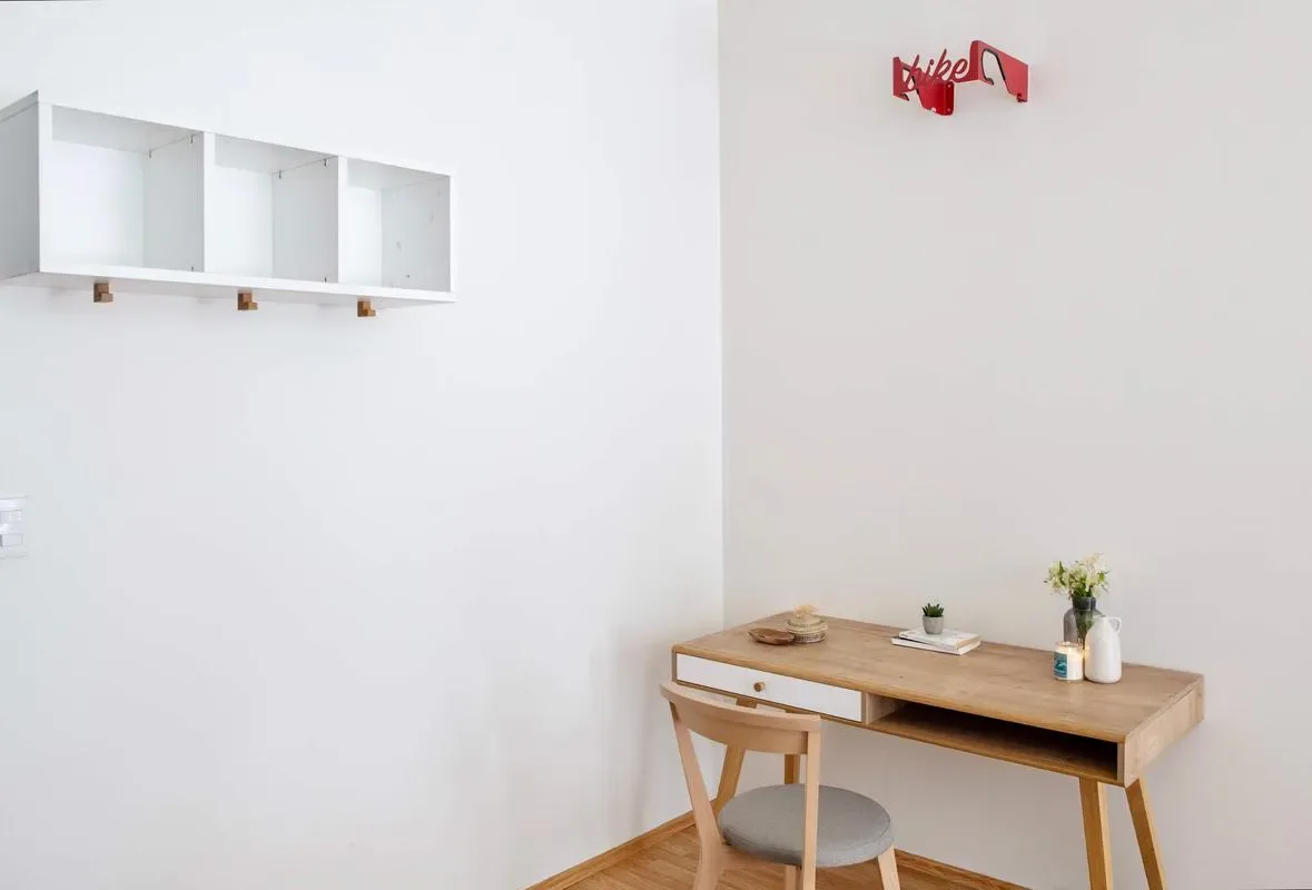 A bright room with a wooden desk, a chair, and wall shelving.