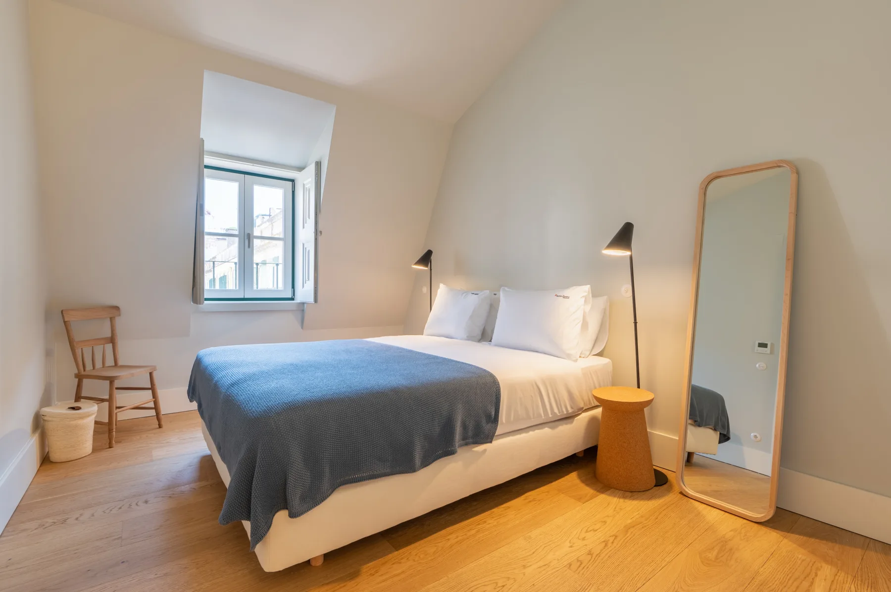 Un dormitorio con una cama, una ventana y un espejo de pie.