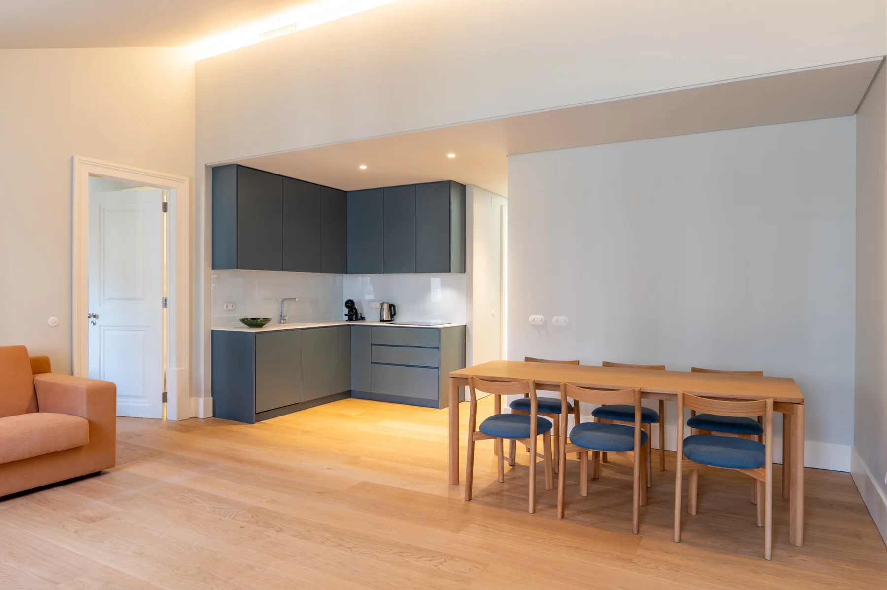 Una luminosa estancia diáfana con cocina, mesa de comedor y zona de estar.