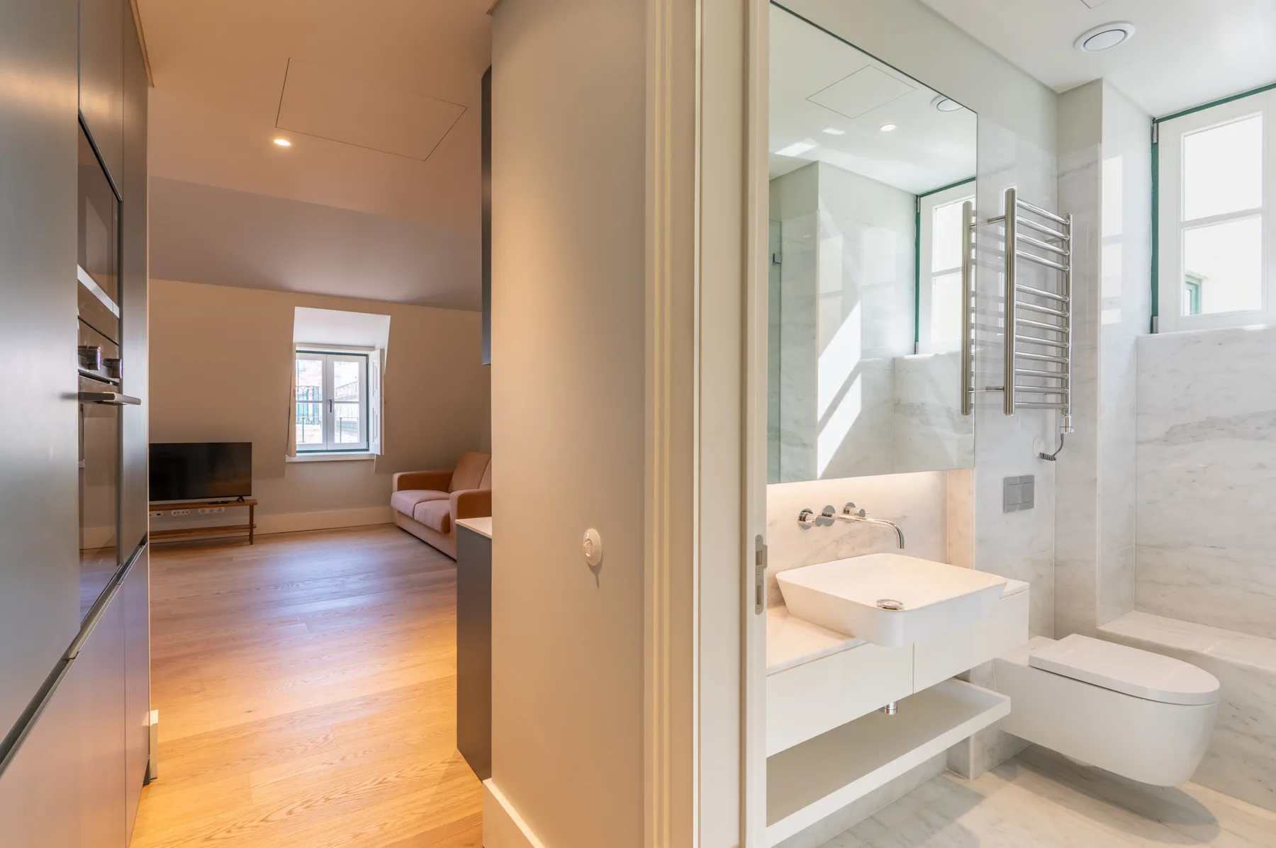Un baño con lavabo y ducha da a una sala de estar con asientos.