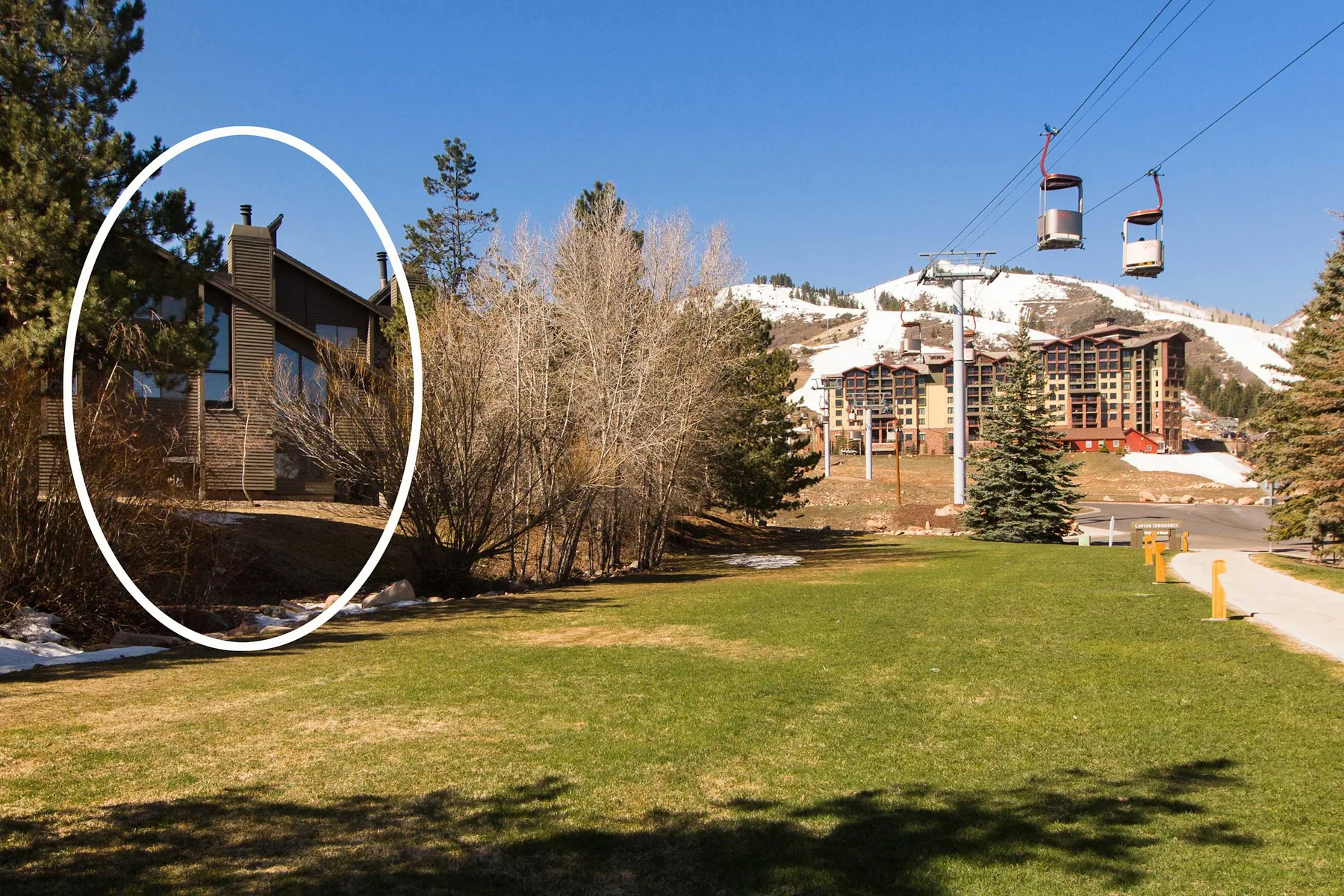 Jardines de un complejo turístico con un alojamiento, árboles y teleféricos en lo alto.