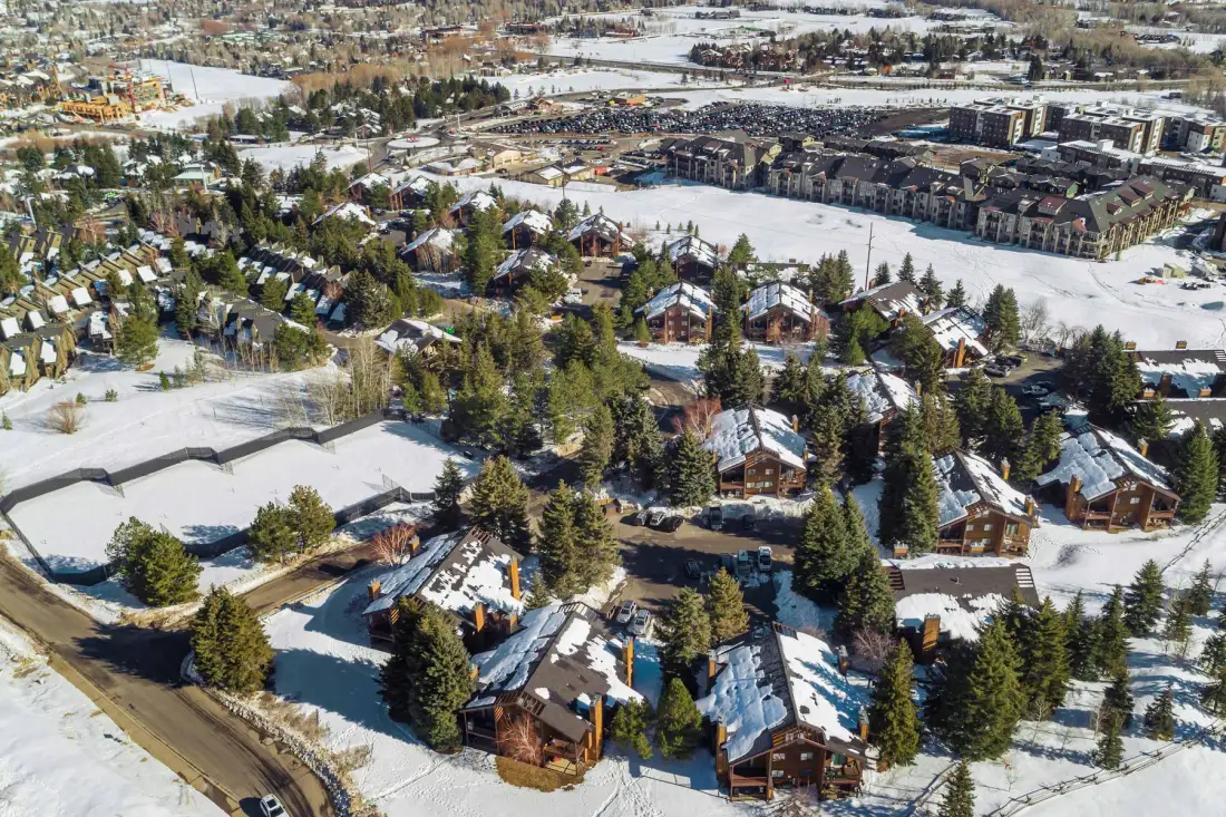 Vista aérea de un vecindario cubierto de nieve, con casas y árboles de hoja perenne.