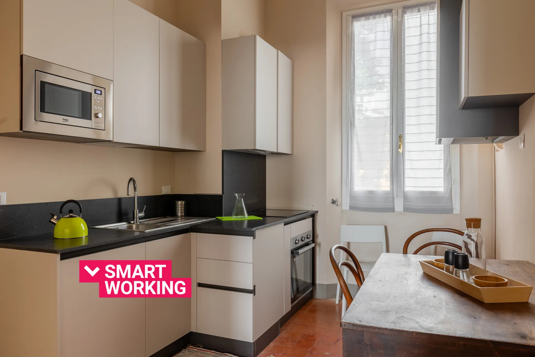 Una cocina compacta con comedor y una mesa junto a una ventana alta.