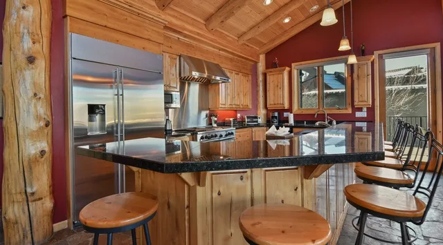 Una cocina con una isla central, encimeras oscuras y gabinetes de madera.
