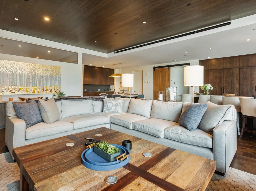 Una amplia sala de estar con un gran sofá seccional y una mesa de centro de madera.