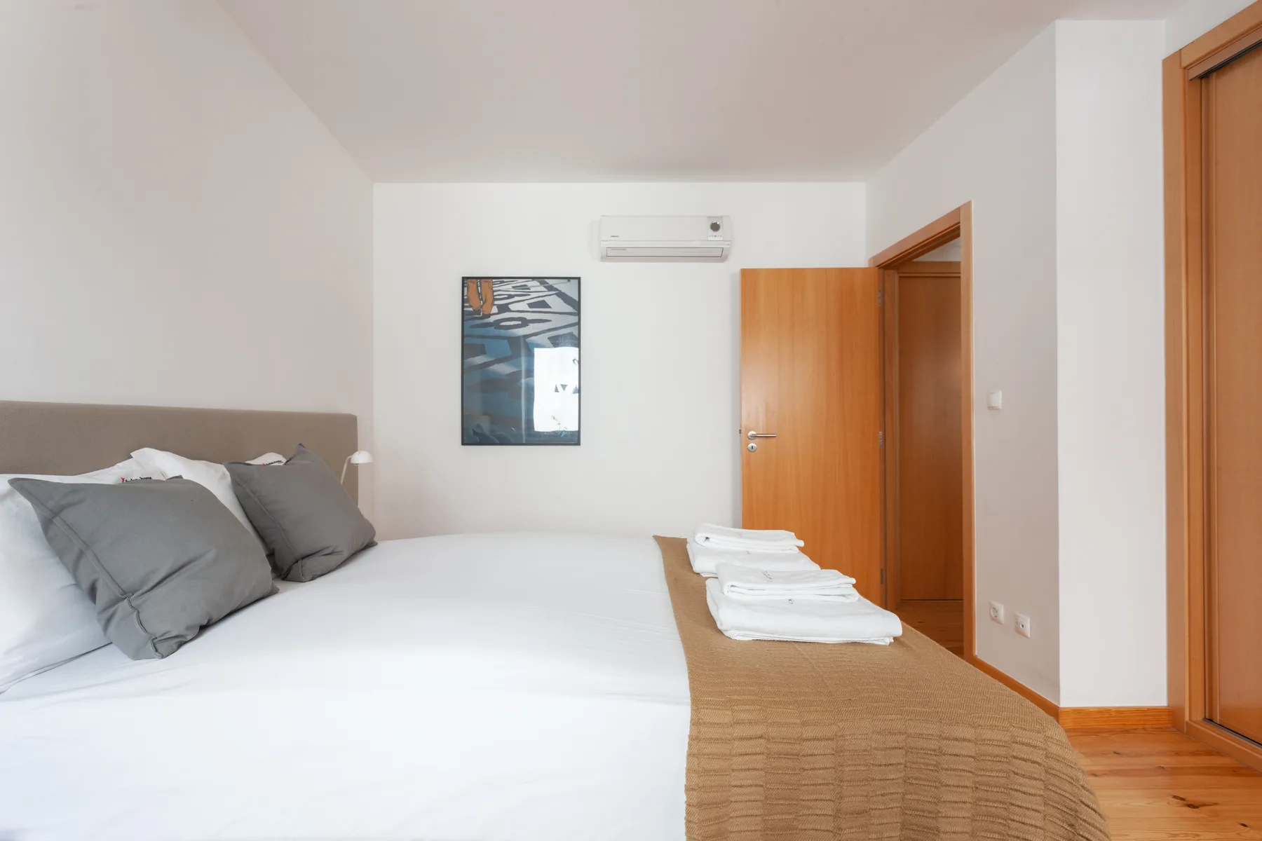 Dormitorio con una cama, toallas dobladas y puertas de madera.
