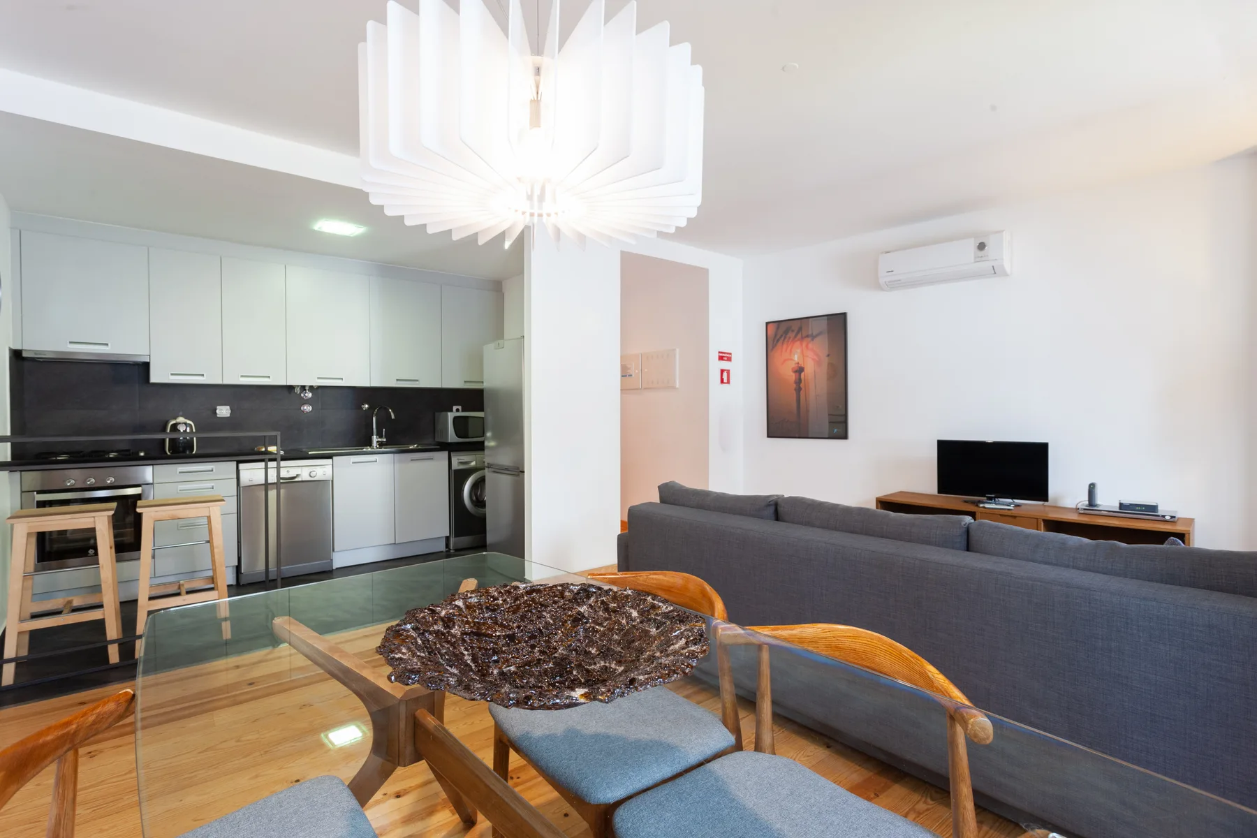 Sala de estar y comedor de planta abierta con cocina y asientos grises.