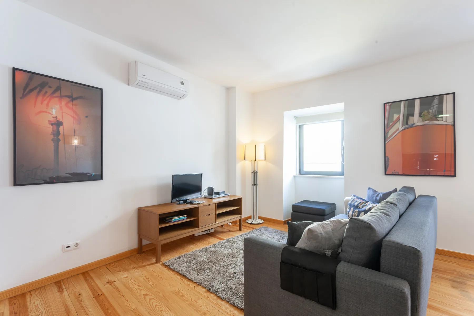 Living room with gray seating, a television, and framed wall art.