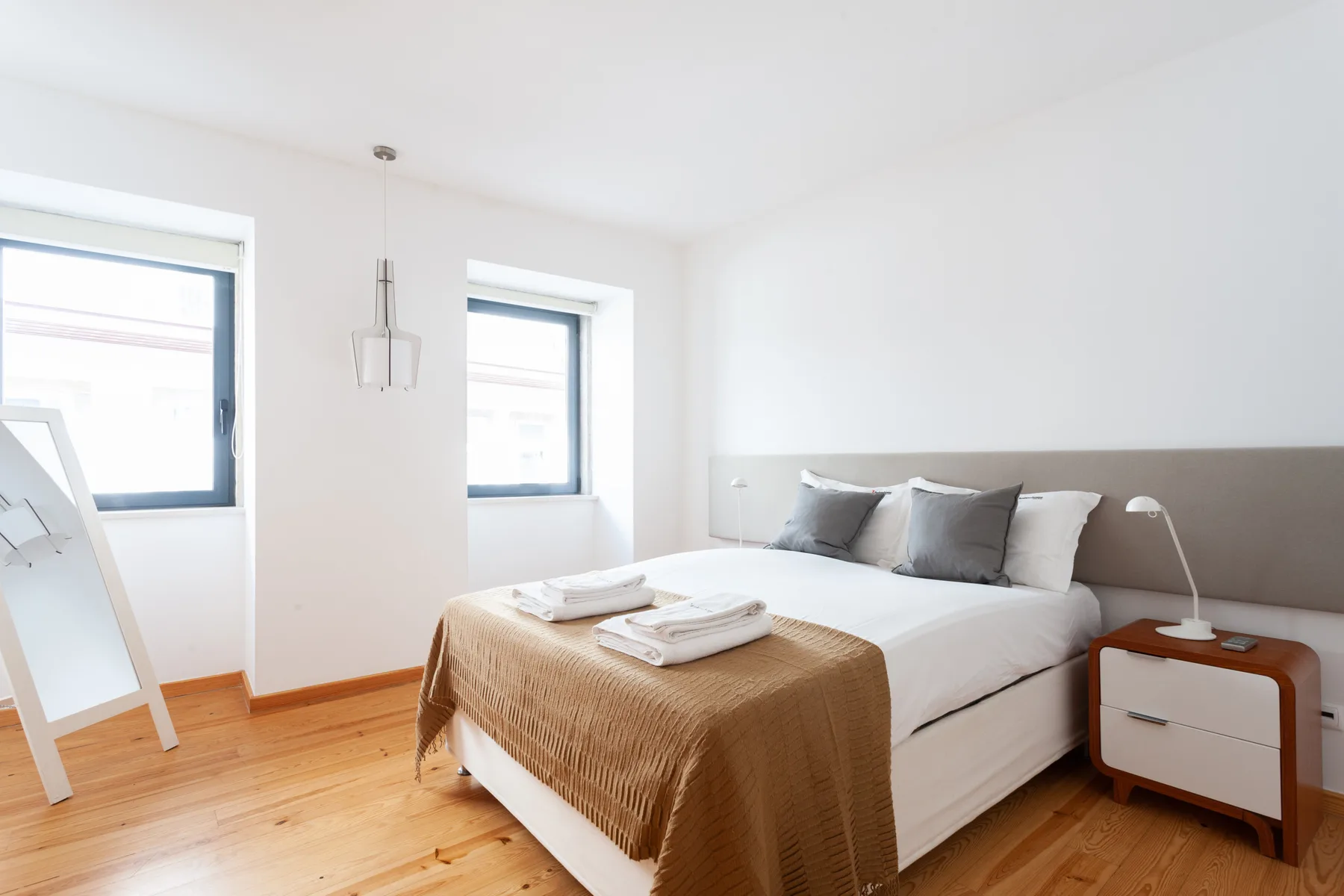 Un dormitorio luminoso con una cama y dos ventanas.