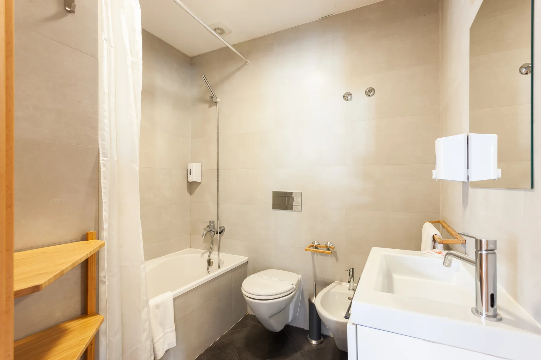 Un baño con azulejos, bañera, inodoro, bidé y lavabo.