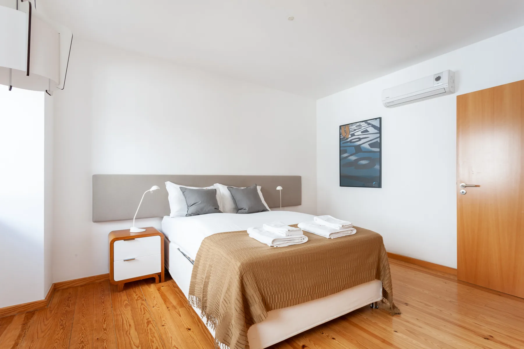 Un dormitorio con una cama, una mesita de noche y aire acondicionado en la pared.