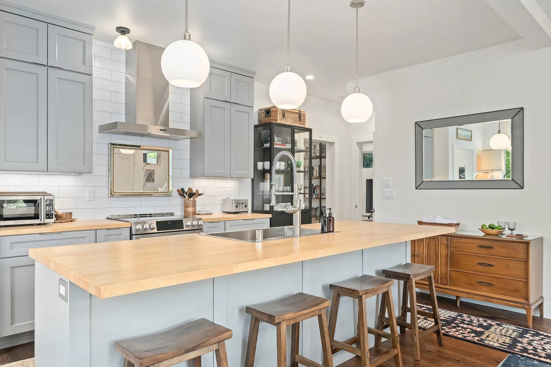 Una cocina luminosa con una gran isla, lámparas colgantes y taburetes.