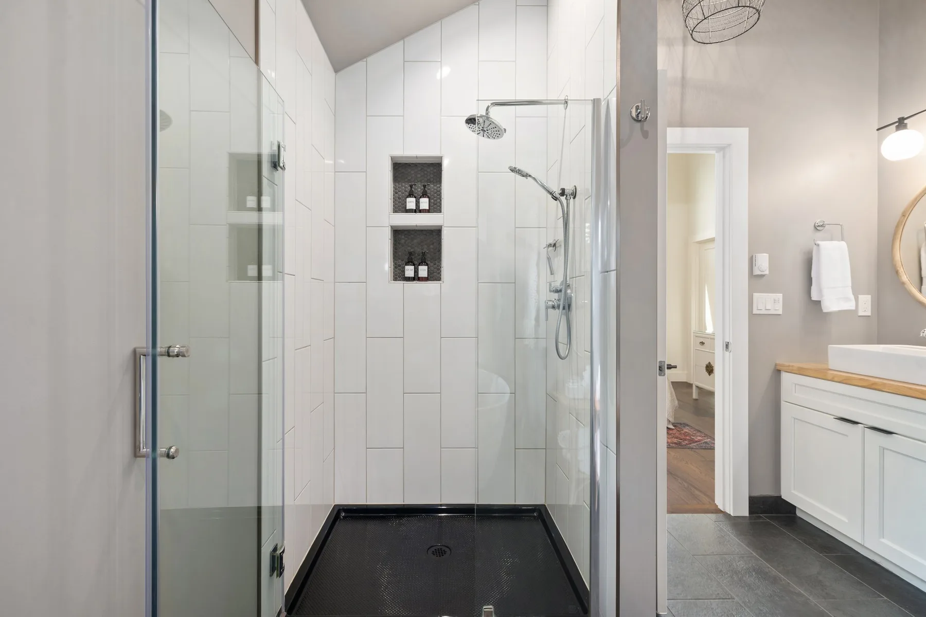 Un baño alicatado con ducha de vidrio y un tocador blanco.
