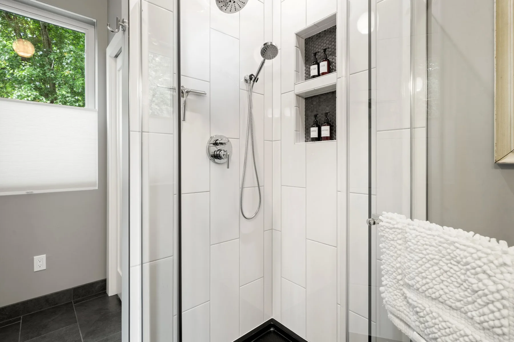 Una ducha de baño con azulejos, estantes empotrados y una toalla.